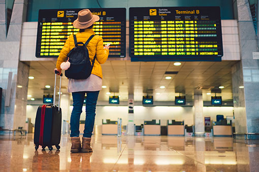 Photographie d'une femme à l'aéroport regardant les tables de départ et d'arrivée
